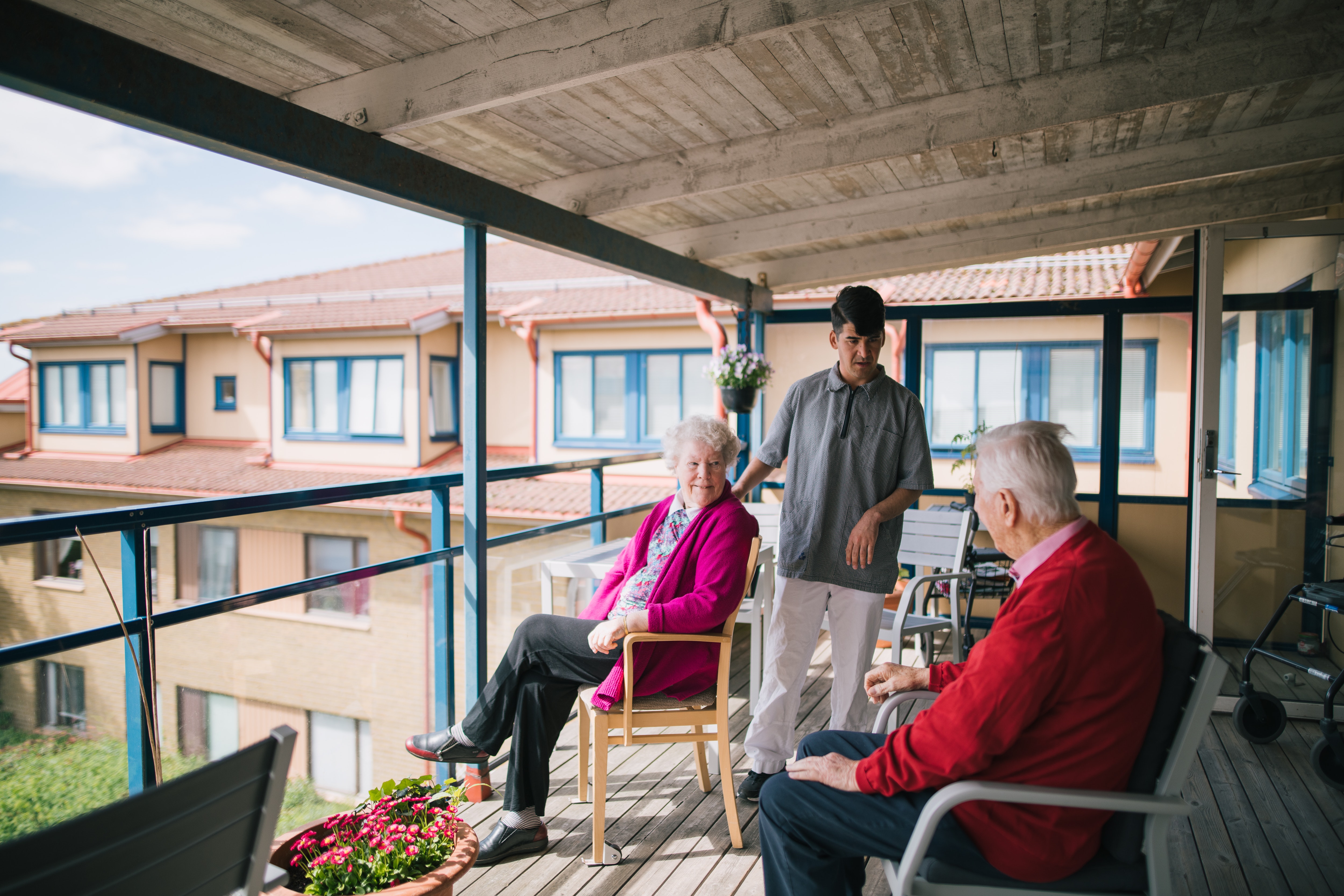 Två äldre personer sitter på en balkong på äldreboendet Solhöjden och pratar med en anställd.