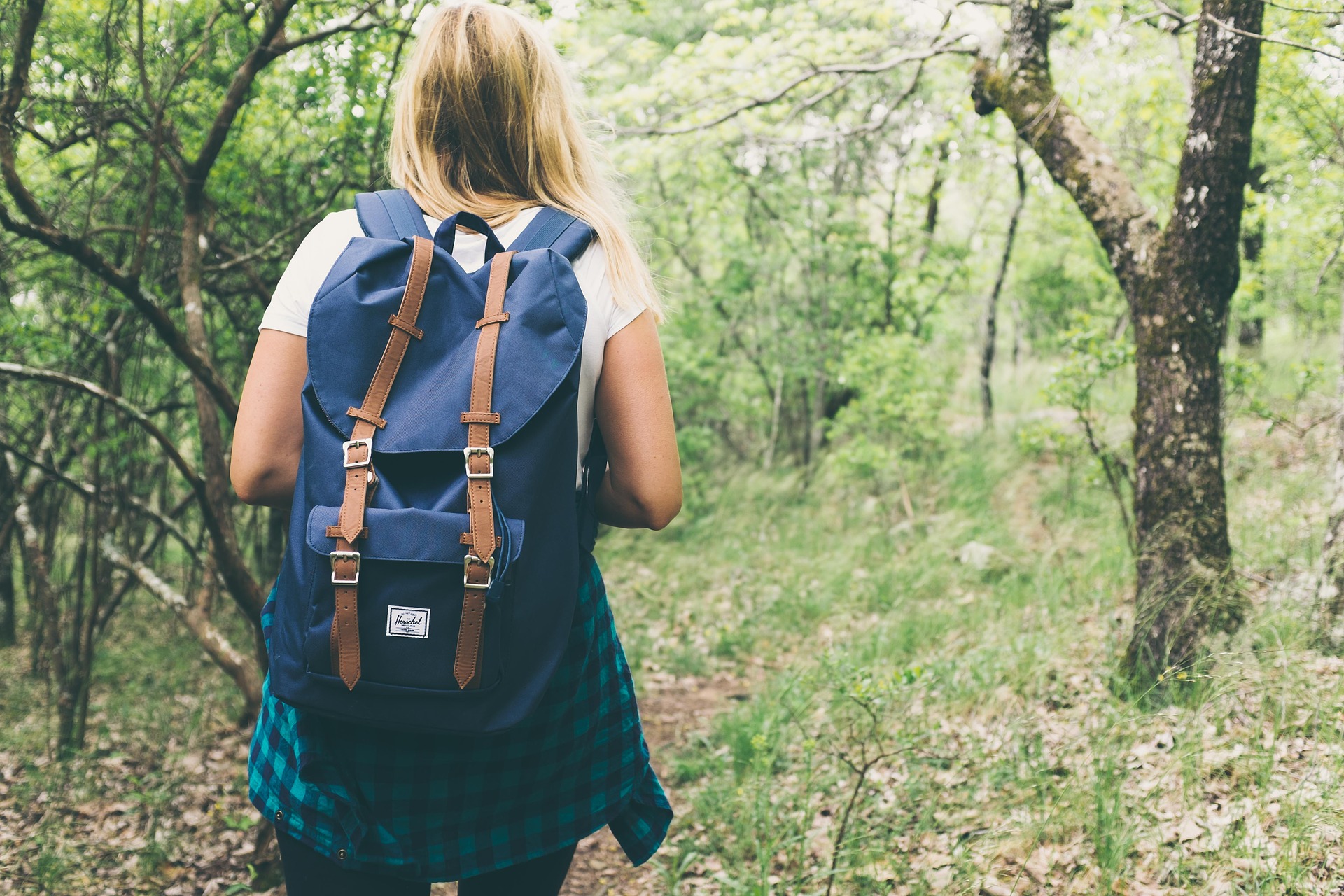 tjej går med ryggsäck i skogen