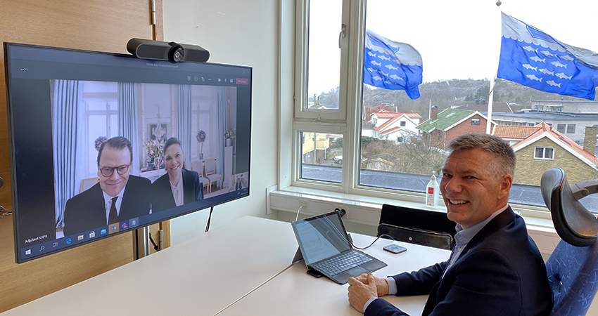 Kronprinsessparet syns på en skärm medan kommunstyrelsens ordförande Jan Utbult sitter framför skärmen.