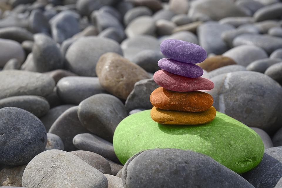 Byggstenar för din hälsa. Bilden visar en strand med stenar som ligger på varandra i olika färger.